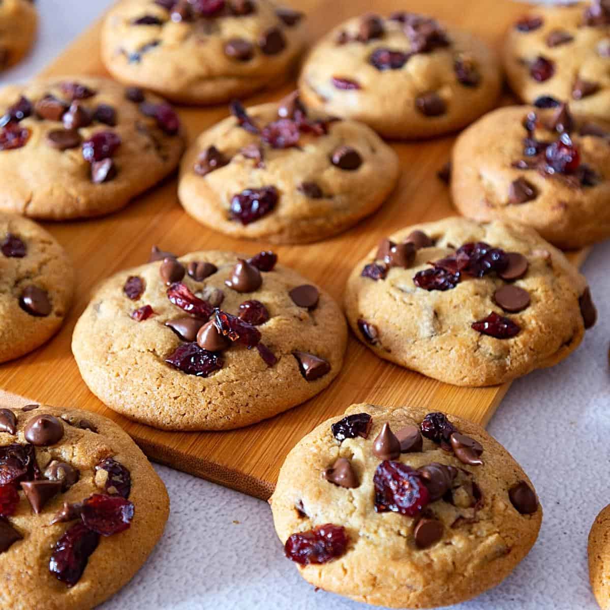 Cookies on a wooden board with chocolate and cranberries.