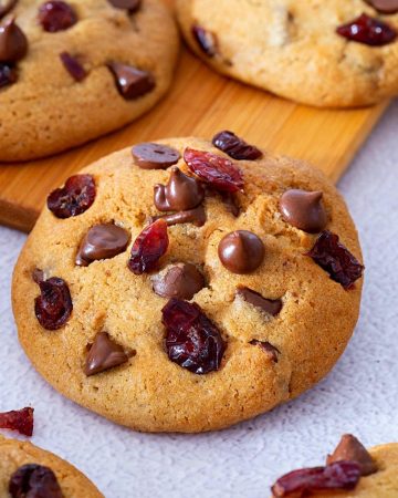 A cook with chocolate and cranberries on a table.