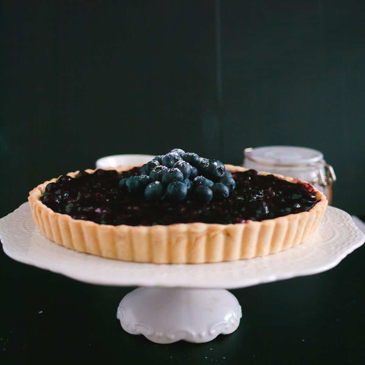 A blueberry tart on a cake stand.
