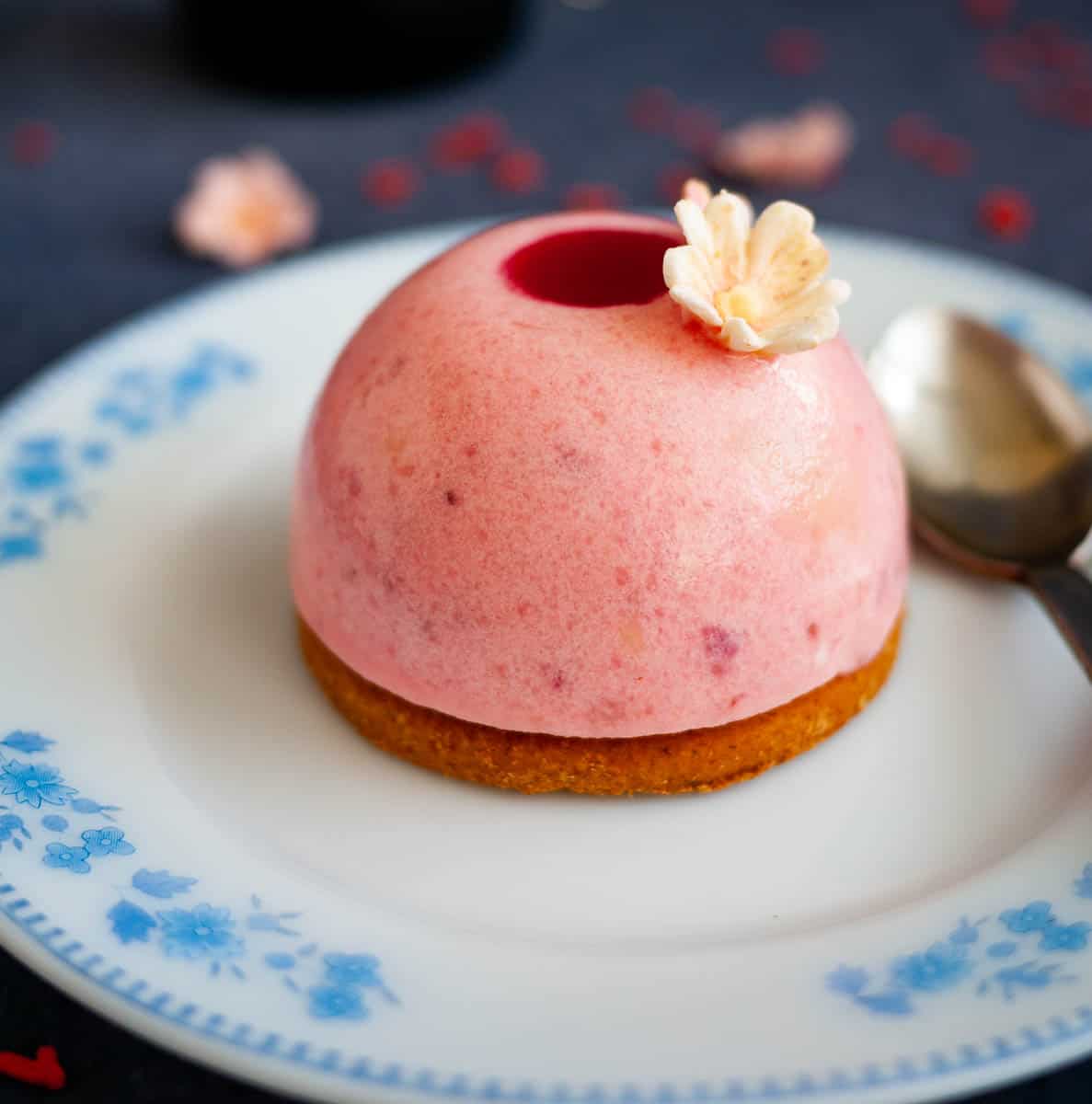 A white plate with strawberry mousse dome