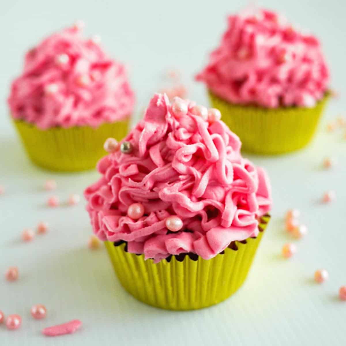 Pink frosted cupcakes on the table.