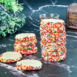 A black marble table with cookies made with sprinkles.