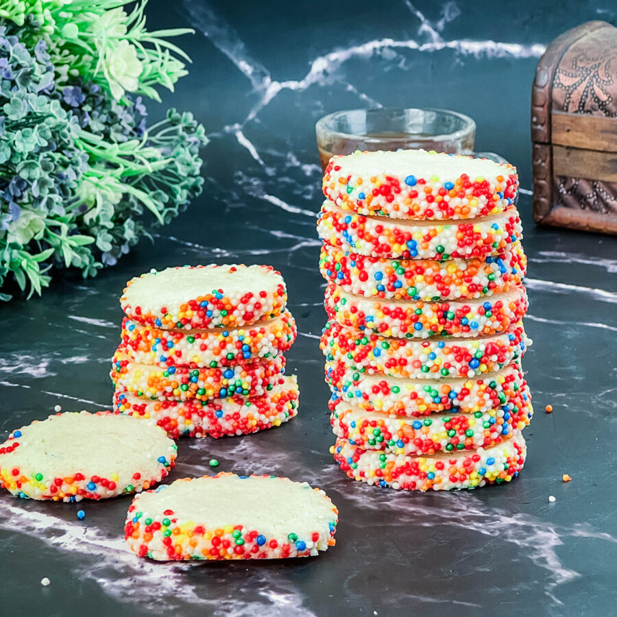 A black marble table with cookies made with sprinkles.