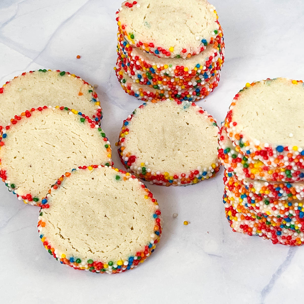 White table with sliced and baked sprinkle cookies.