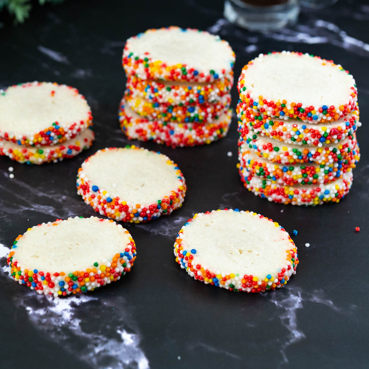 Buttery cookies with sprinkles on a black marble.