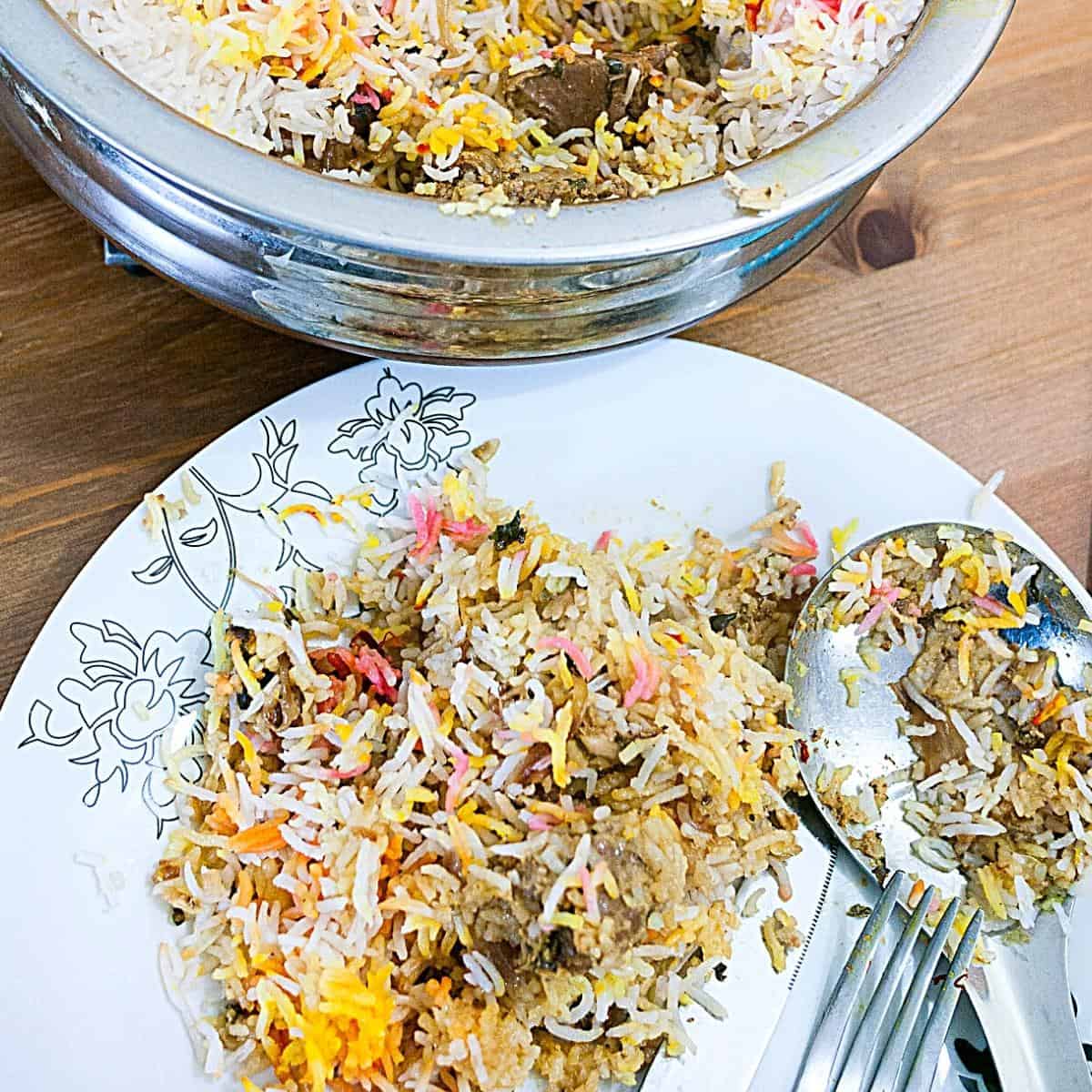 A plate with biryani and lamb cubes.