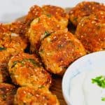 Fish cakes on a plate with yogurt dressing.