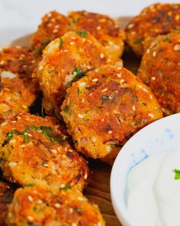 Fish cakes on a plate with yogurt dressing.