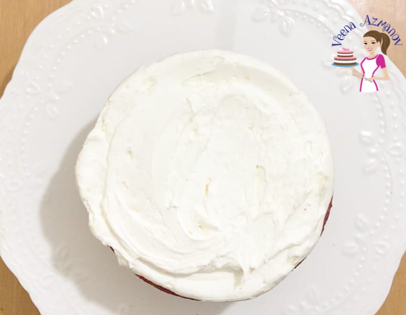 Frosting the red velvet layers with cream cheese frosting