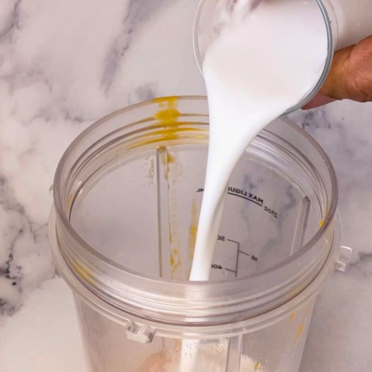 Adding coconut milk to the blender.