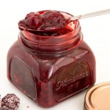 A mason jar and spoon with blackberry filling for cakes, pies, tarts, desserts.
