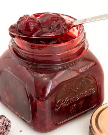 A mason jar and spoon with blackberry filling for cakes, pies, tarts, desserts.