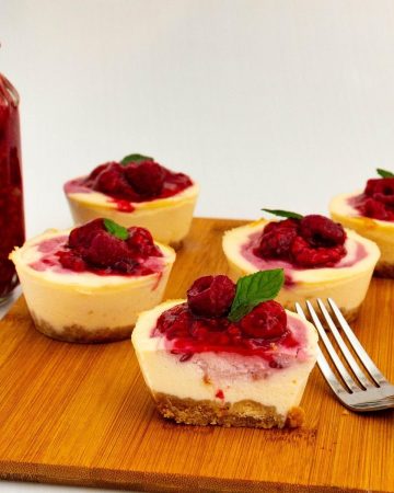 Sliced mini cheesecakes topped with raspberries.