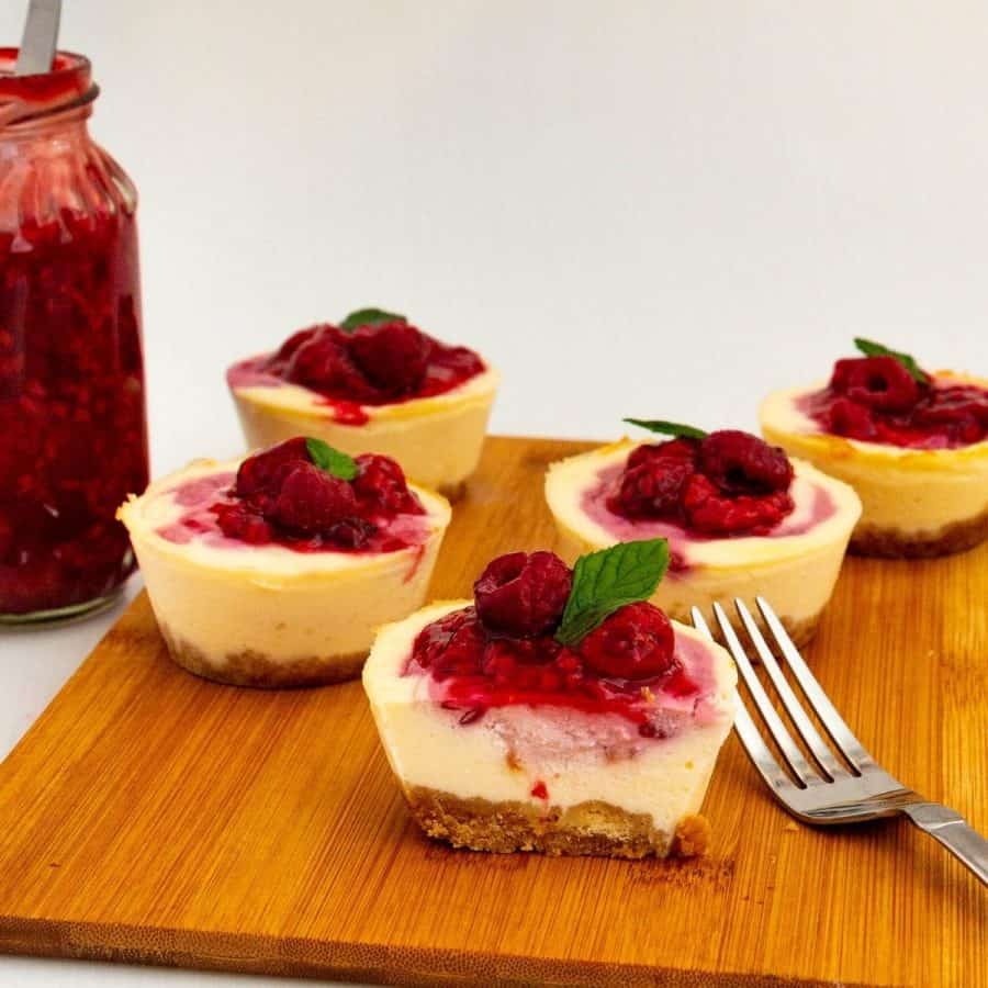 Sliced mini cheesecakes topped with raspberries.