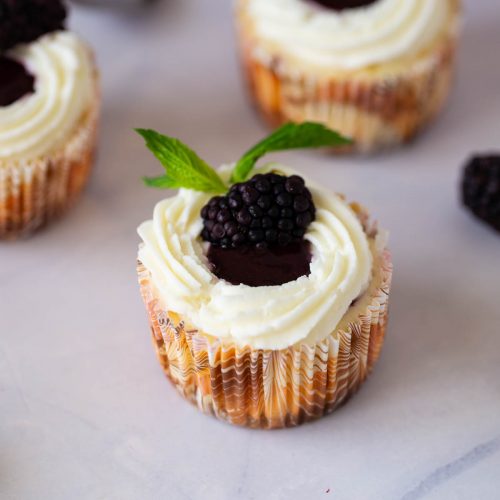 A frosted blackberry cheesecakes on the table.
