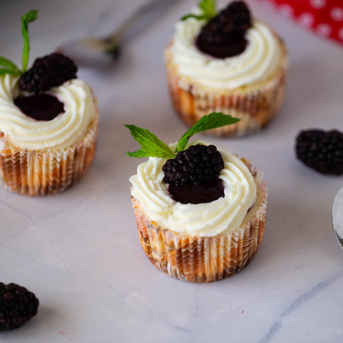Frosted blackberry cheesecakes on the table.