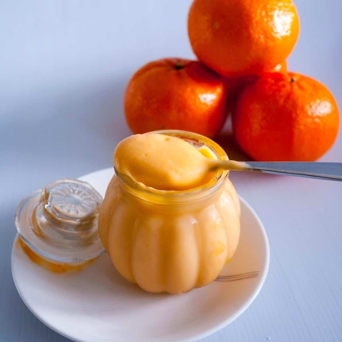 A jar and spoon with curd filling and oranges