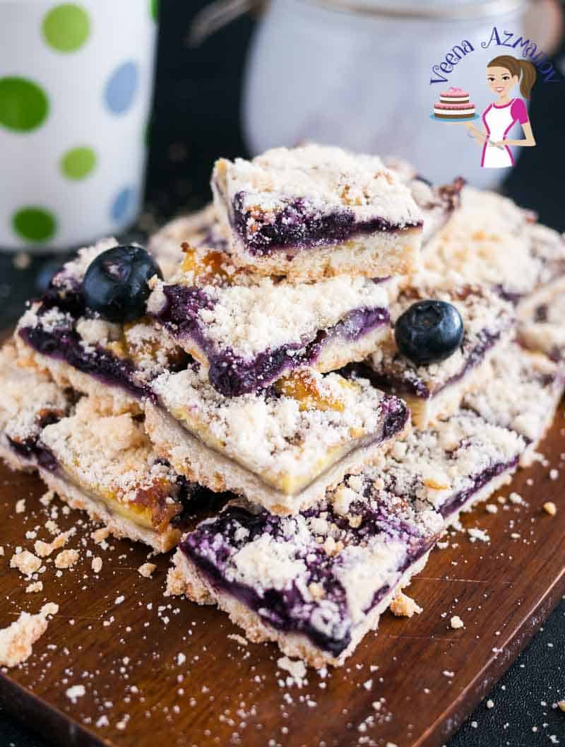 A stack of blueberry cake squares on a wooden board.