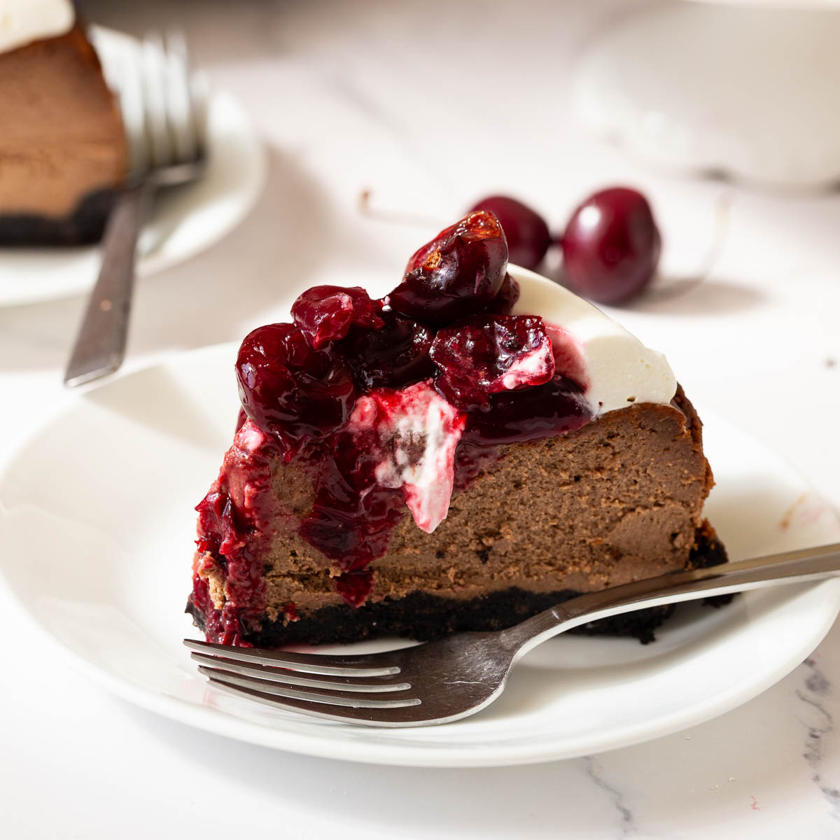 A slice of chocolate cheesecake with cherry topping.