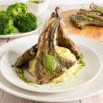 A plate with lamb chops over mashed potato.