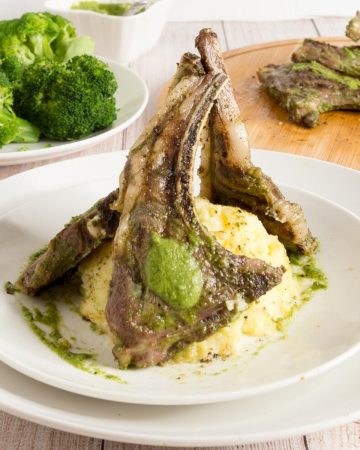 A plate with lamb chops over mashed potato.