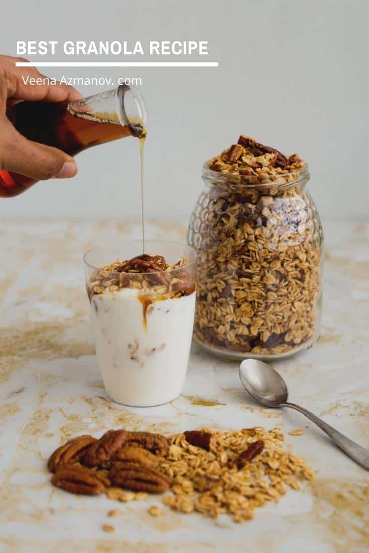 A person pouring maple syrup to glass full of yogurt and granola.