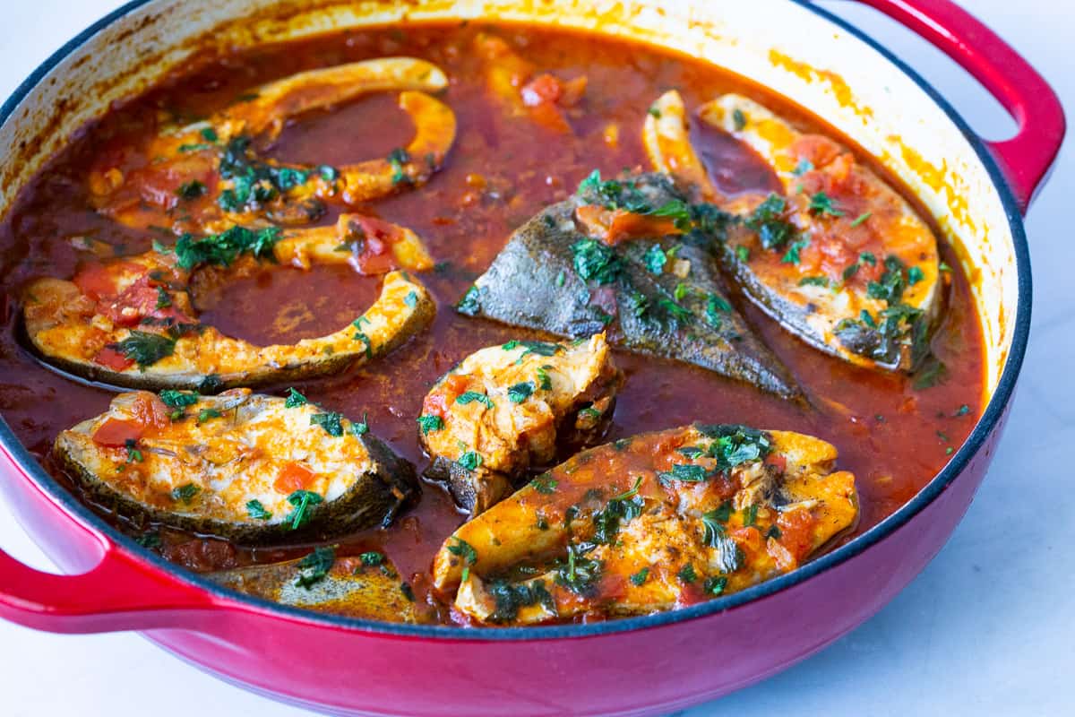 A skillet with fish and tomato sauce.