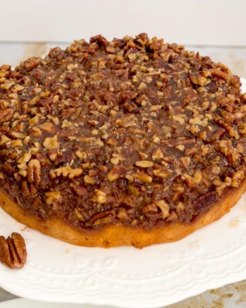 An inverted pecan pie cake on a cake stand.