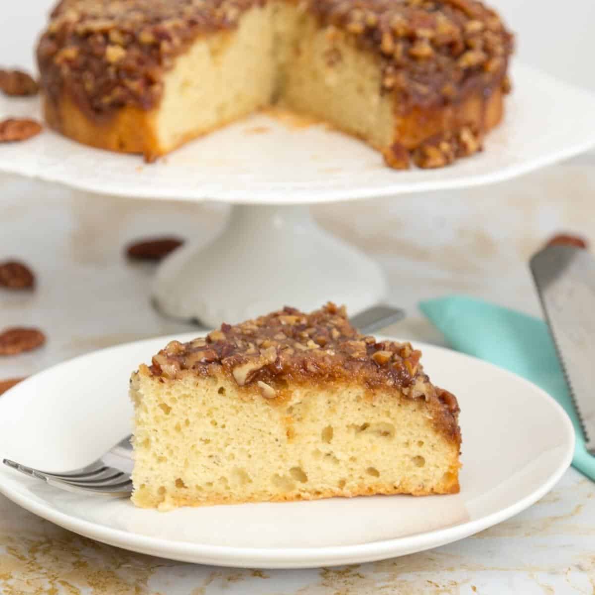 A slice of cake with pecan pie topped on a cake stand.