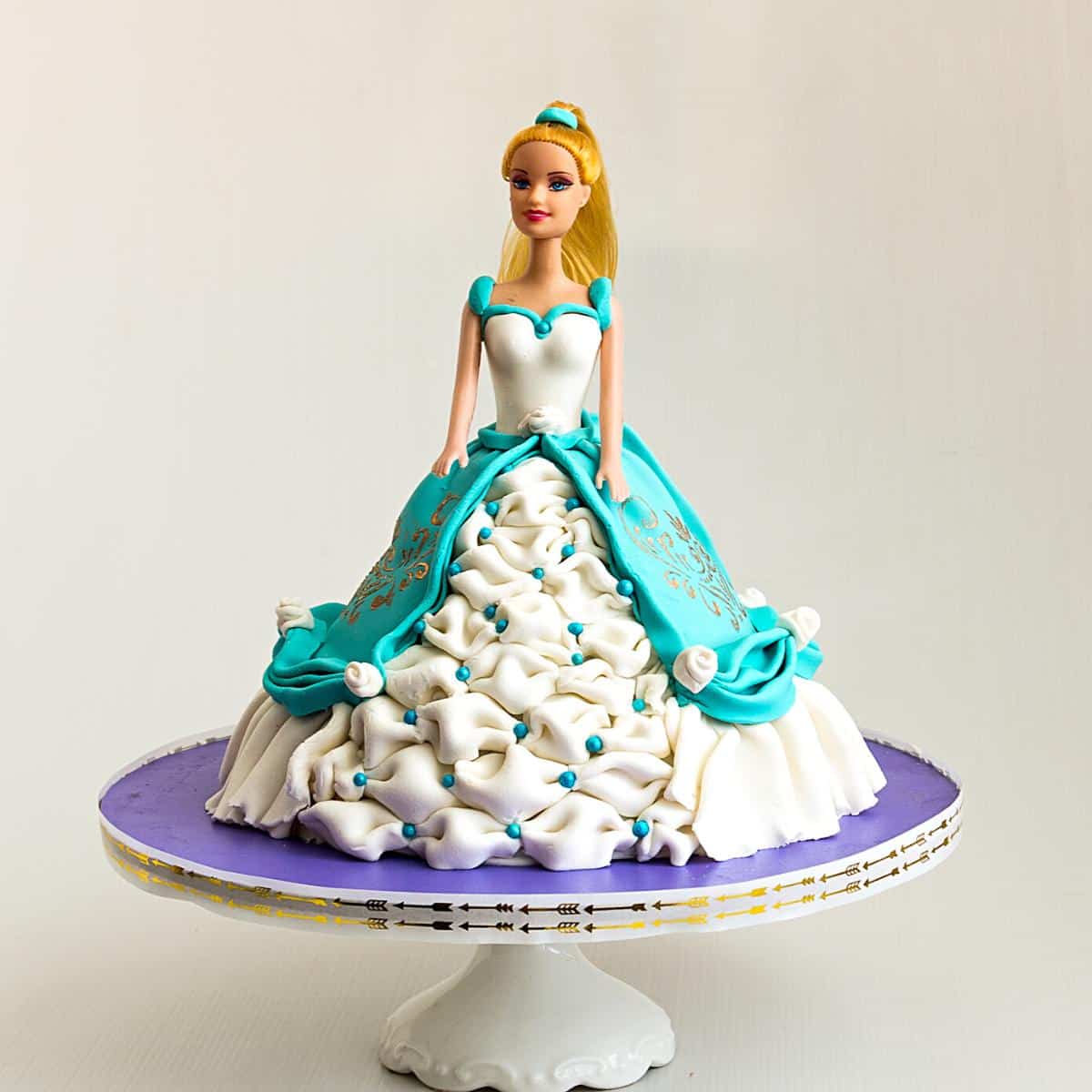 A doll cake on the cake board.