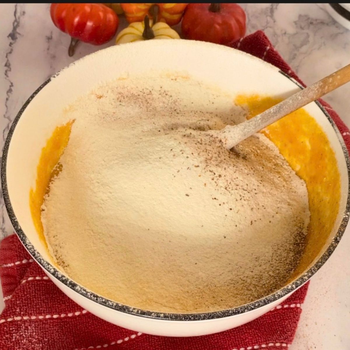 Adding the flour mixture with spices to the pumpkin batter.