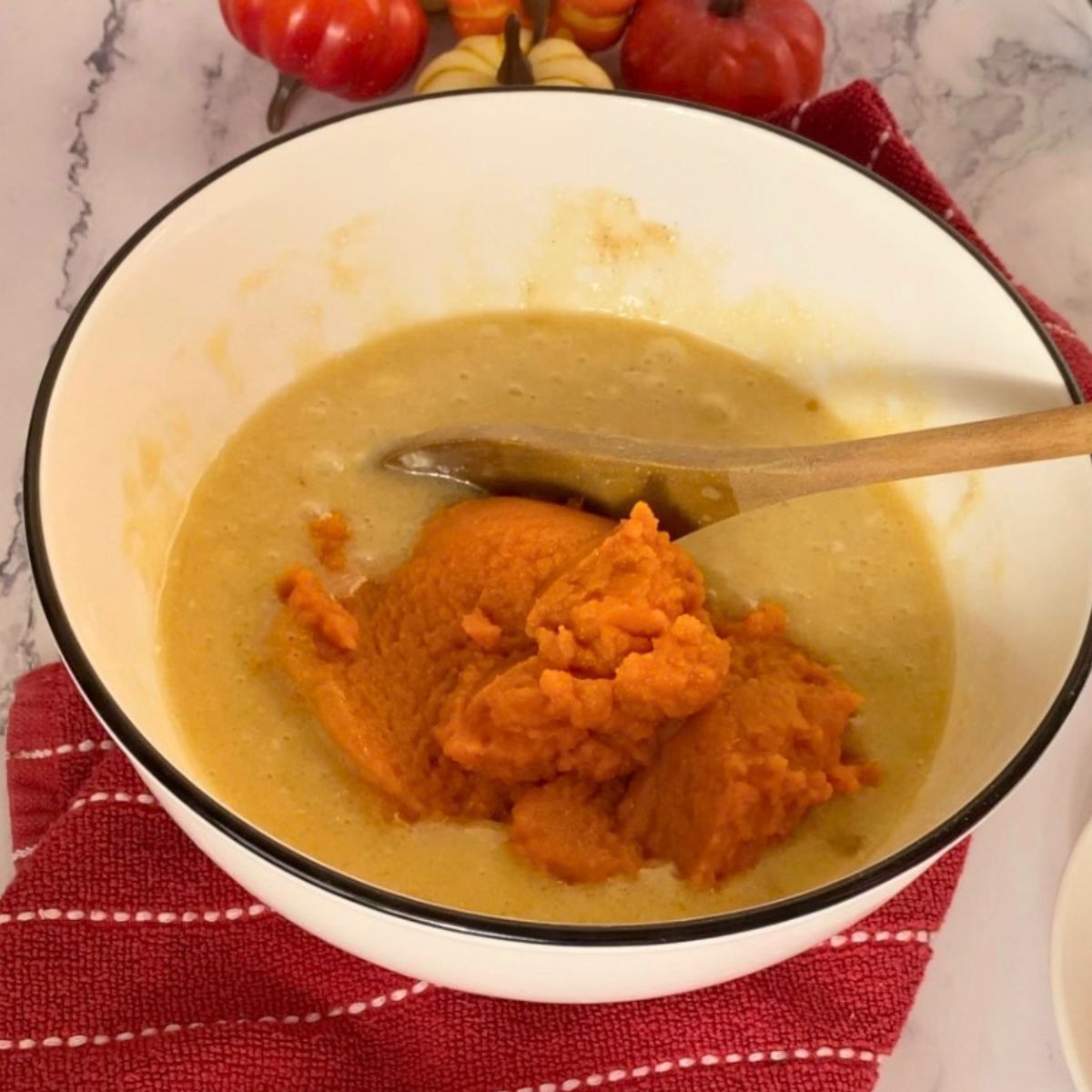 Adding pumpkin puree to the cake batter.