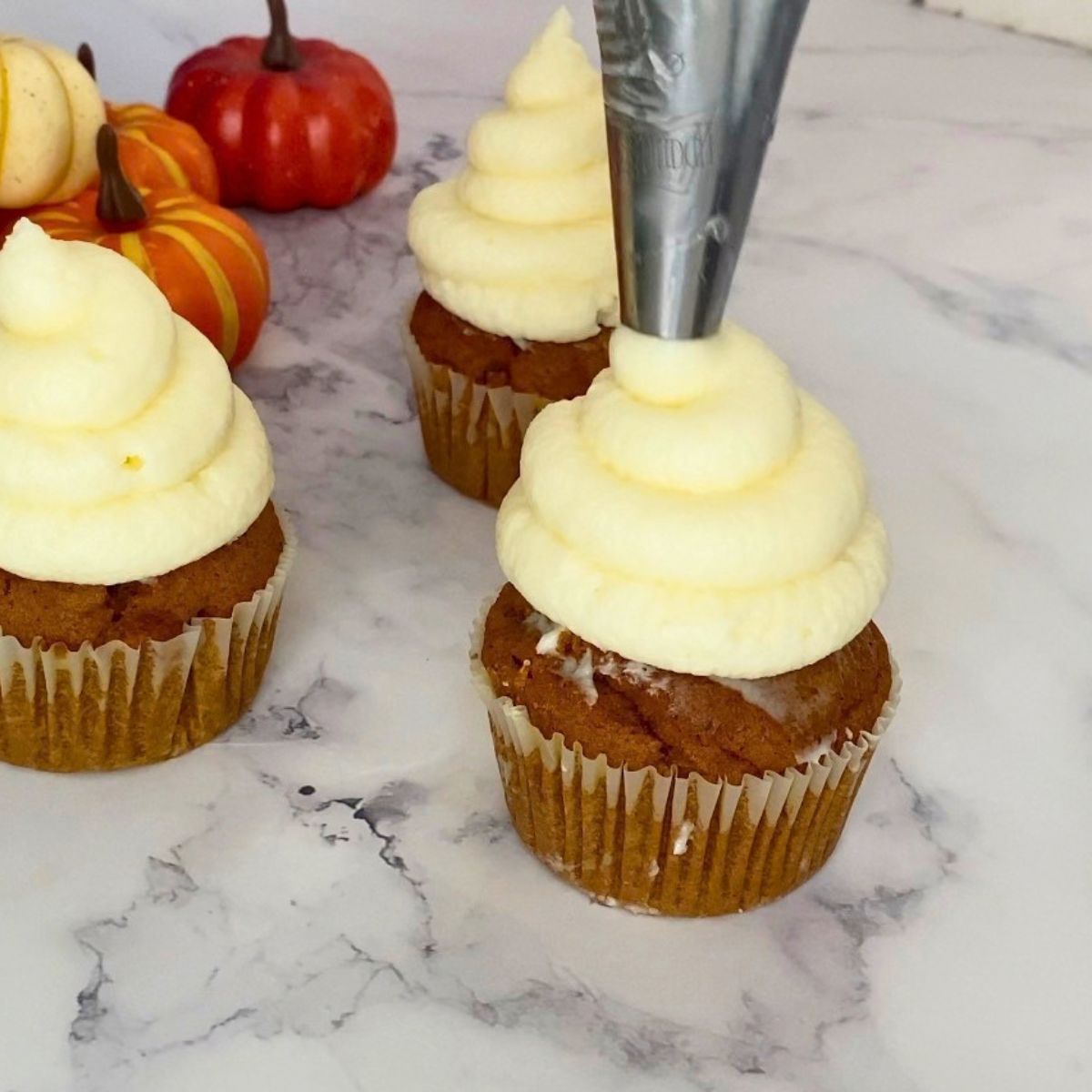 Frosting the pumpkin cupcakes.