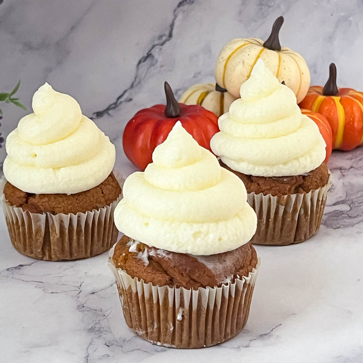 Pumpkin cupcakes frosted with cream cheese frosting.