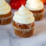 Pumpkin cupcakes frosted with cream cheese frosting.