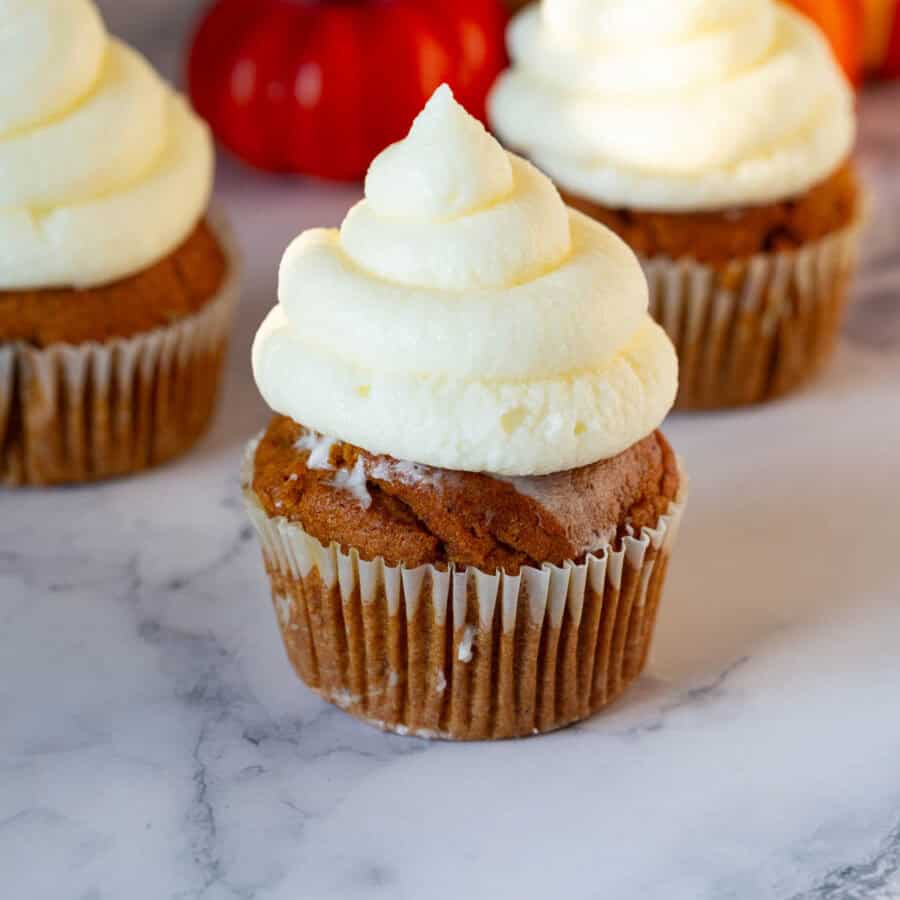 Pumpkin cupcakes frosted with cream cheese frosting.