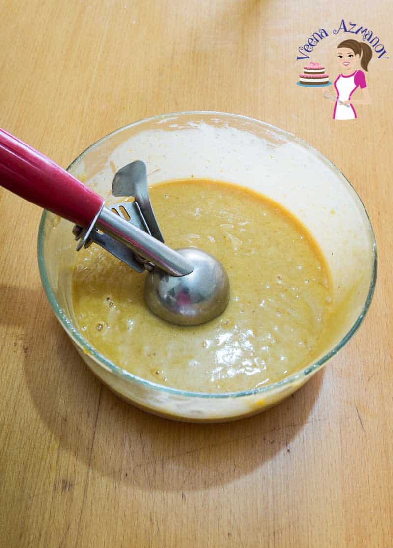 A bowl with pumpkin cupcake batter and an ice cream scooper.