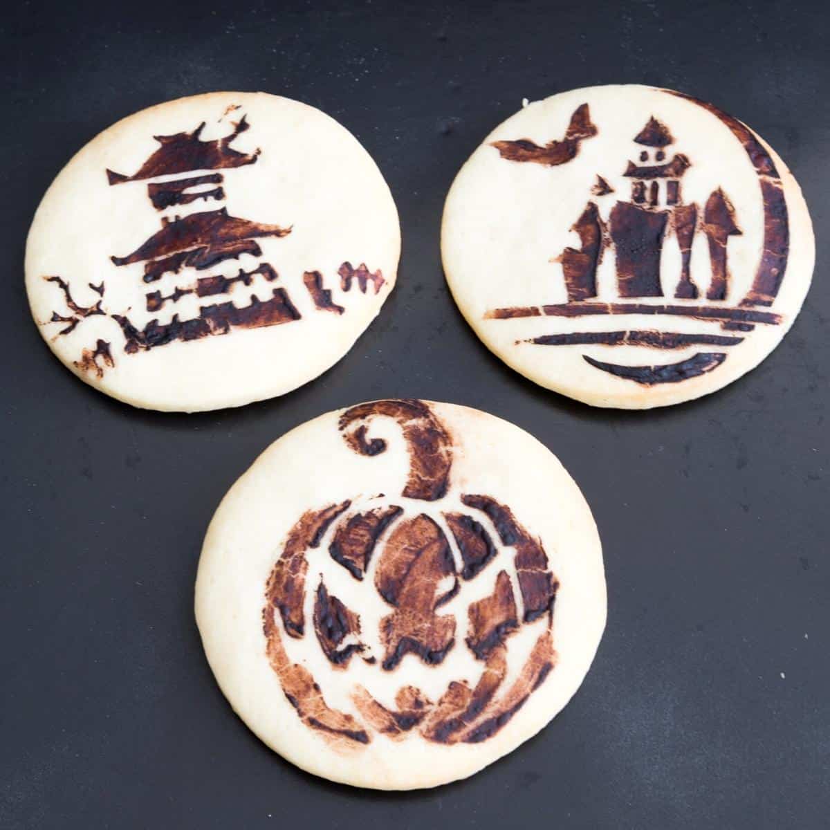 Halloween stenciled cookies on a board.