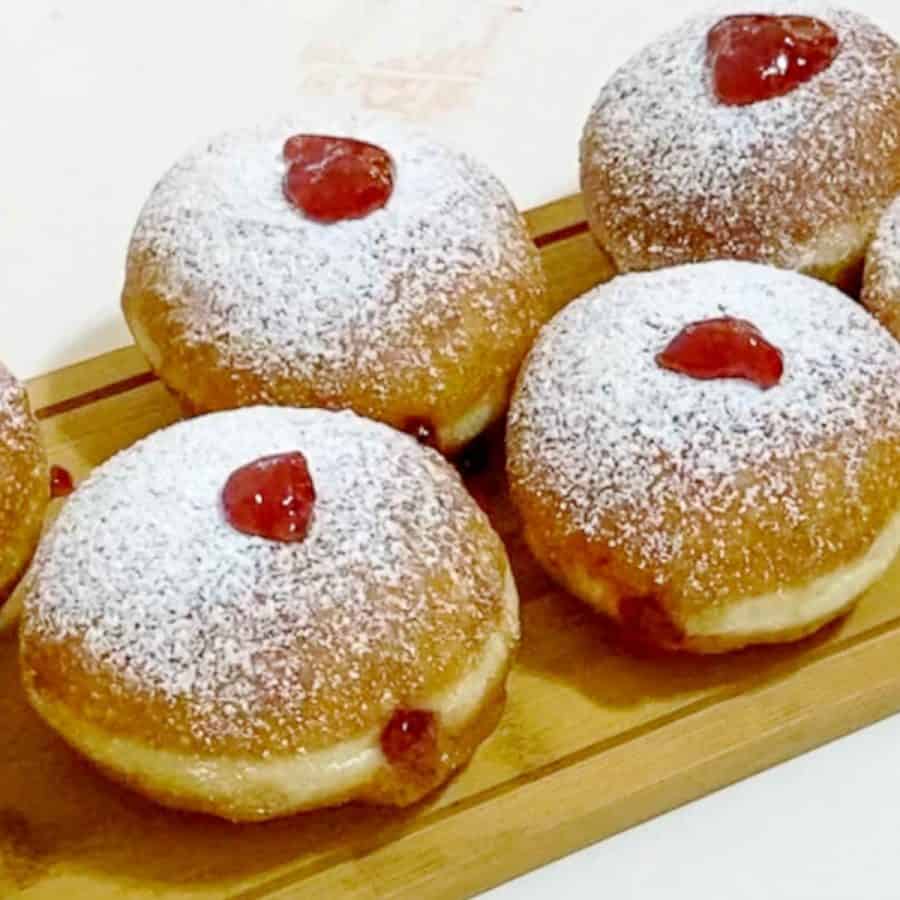 Jelly filled donuts on a wooden board.