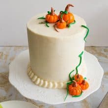 A frosted cake with cream cheese and fondant pumpkins.