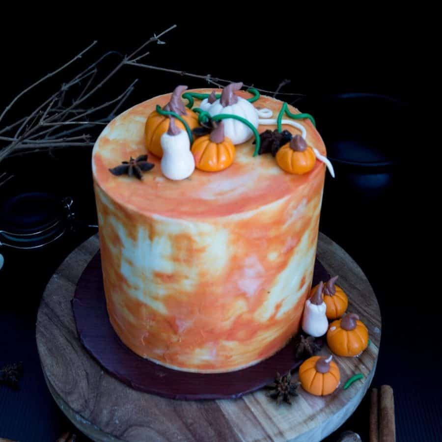 A frosted cake with fondant pumpkins on top