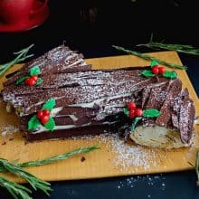 Log cake on a board dusted with cocoa powder.
