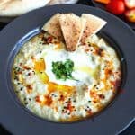 A black plate with baba ganoush and tahini.