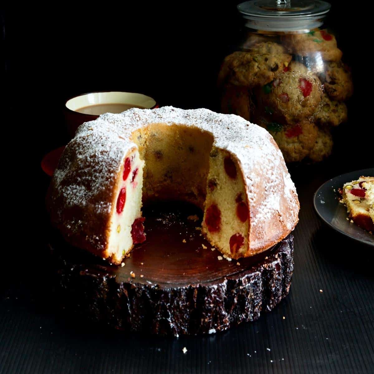 A bundt cake with cherries on a wooden board.