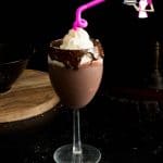 A glass of chocolate eggnog with whipped cream on top.