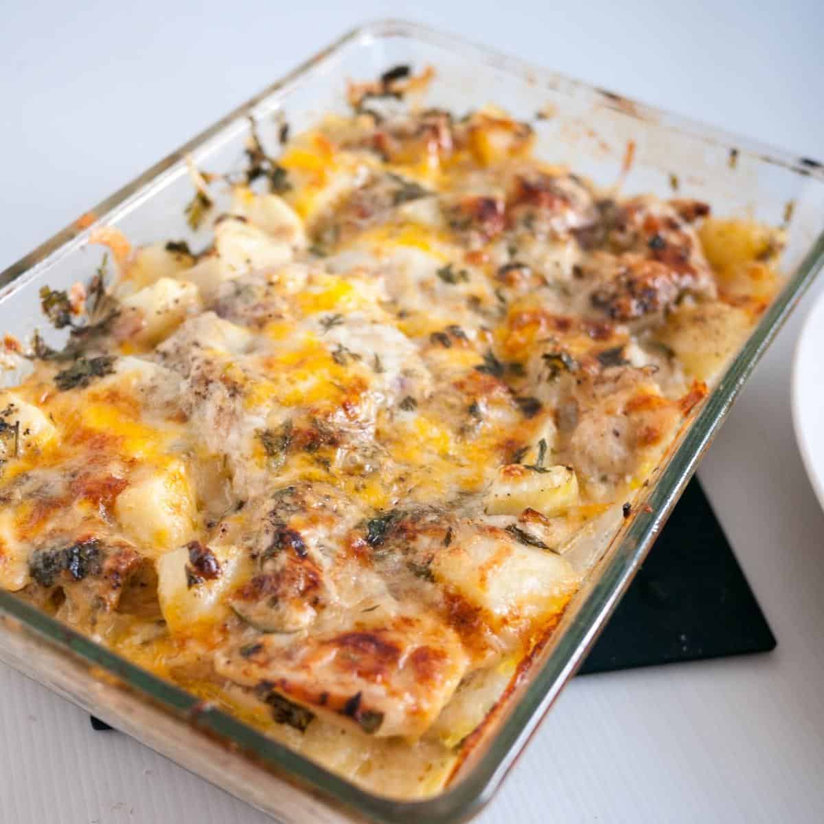 A casserole dish with baked chicken and potatoes.