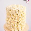 A frosted white wedding cake on a cake stand.
