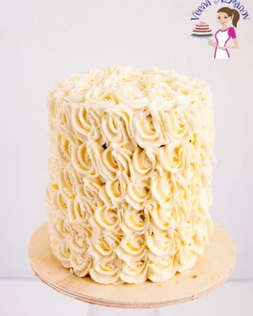 A frosted white wedding cake on a cake stand.