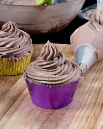 Bakery style frosted cupcake on a wooden table.