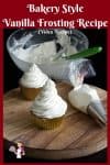 Two cupcakes with vanilla frosting on a round board.